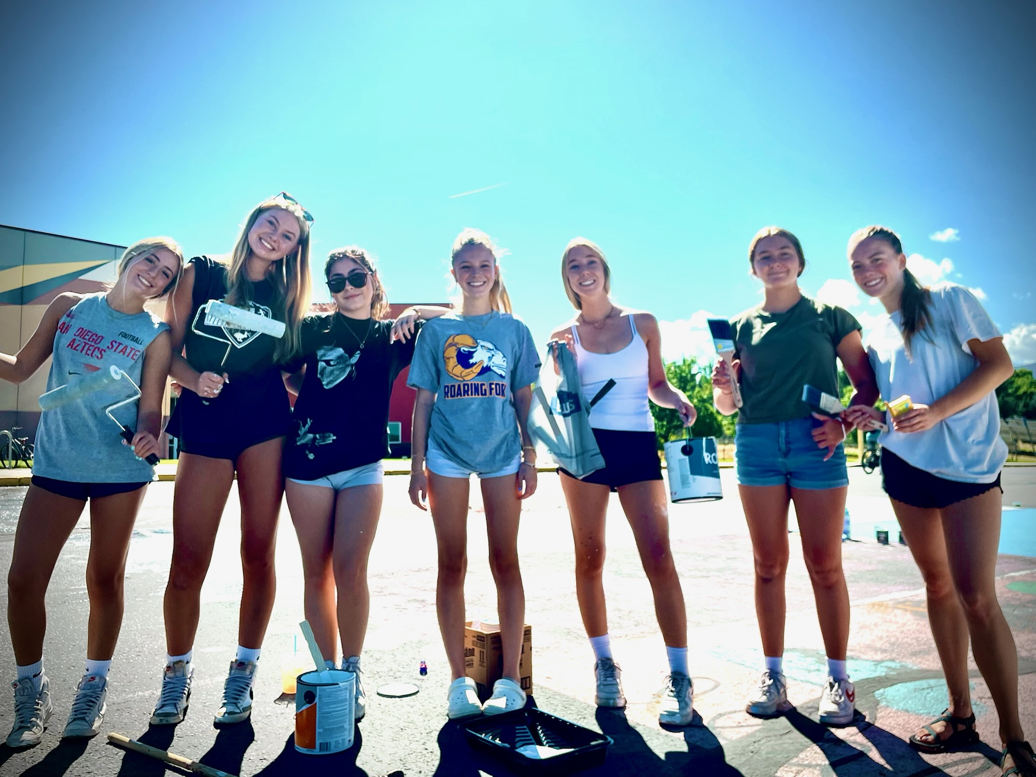Seniors posing with painting supplies in the parking lot